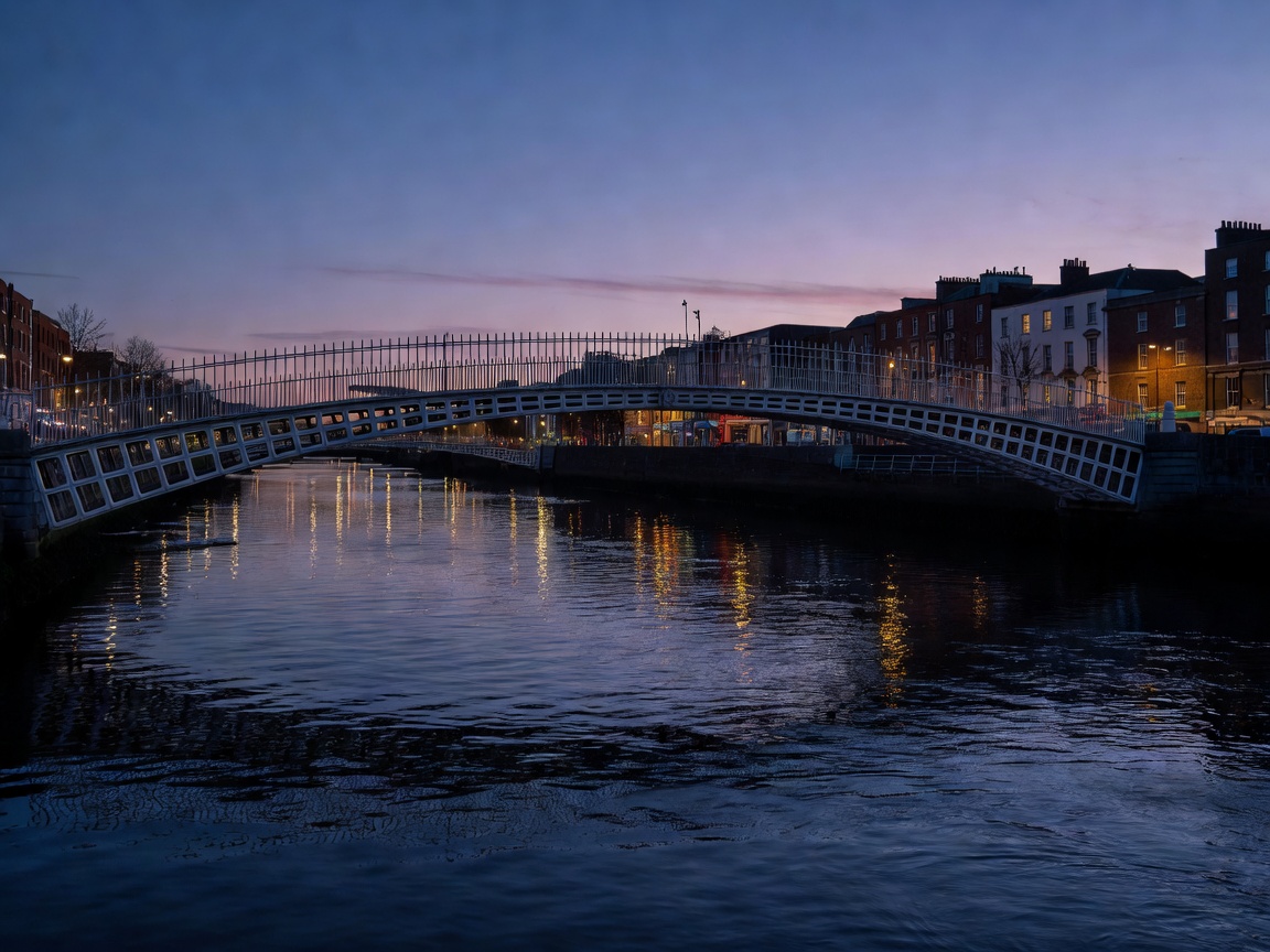 Historic cast-iron Ha penny Bridge illuminated over the River Liffey in central Dublin at twilight